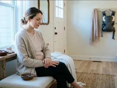 A parent on a couch, infant nestled on their chest, both still and quiet, representing the themes of "Postpartum Anxiety Recovery: What to Expect and How Long It Takes".