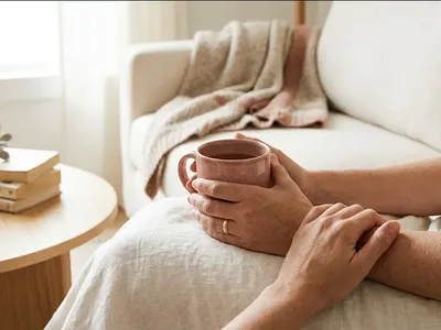 A woman sitting on a bed with a journal open, pen resting, warm morning light, representing the themes of "What to Say to Someone Going Through IVF (A Guide for Friends and Family)".
